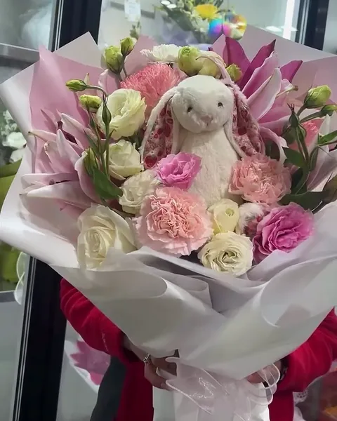 Pink roses with a soft toy bunny tucked in