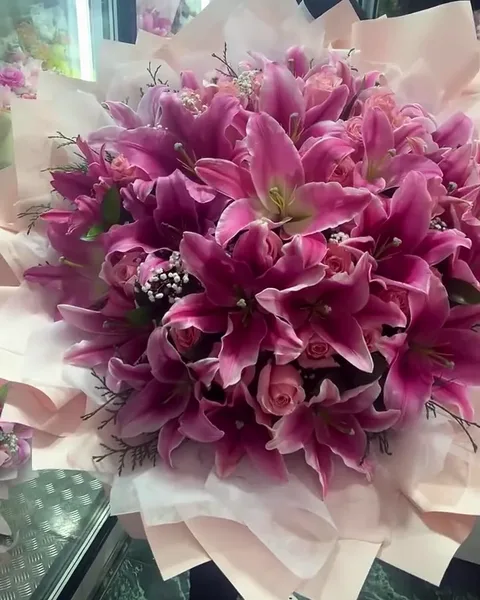 An armful of pink stargazer lilies and pink roses in blush wrap