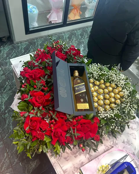 Red roses in a gift box with chocolates and a bottle
