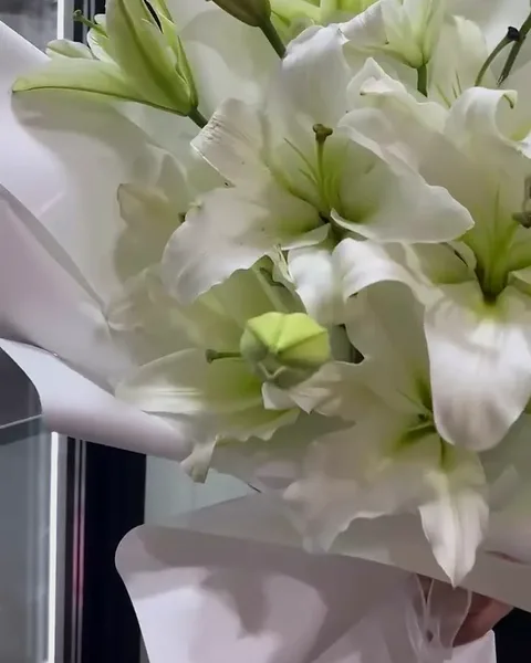A tall bouquet of white lilies in white wrap