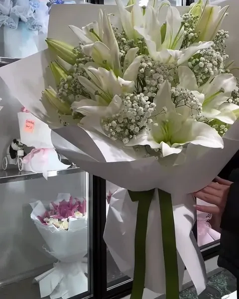 White lilies with baby’s breath in white wrap