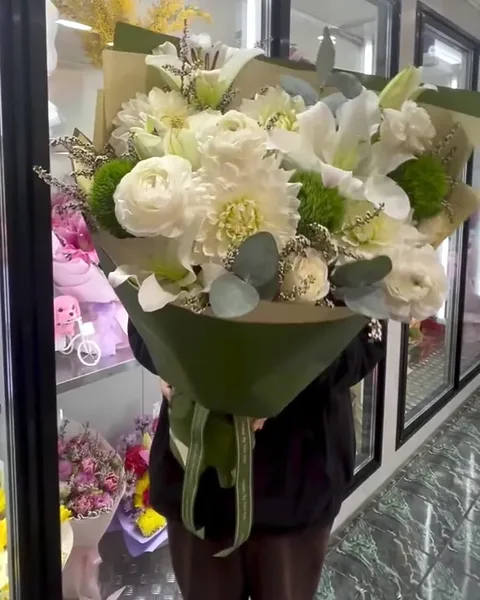White ranunculus, dahlias and lilies in deep green wrap