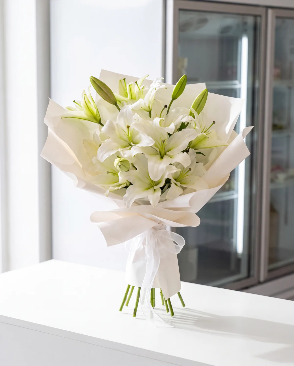 Their bouquet of white lilies in white wrap, on a white bench